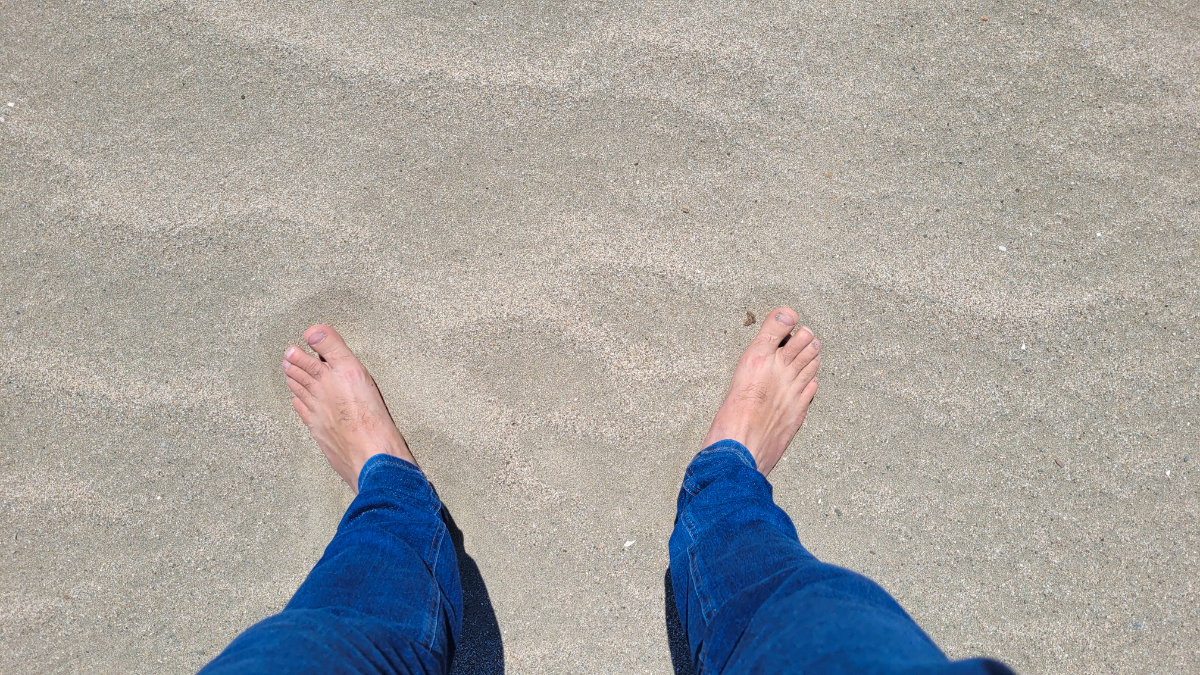 Füsse im Sand am Strand von Camping El Molino – Vanlife Costa Brava